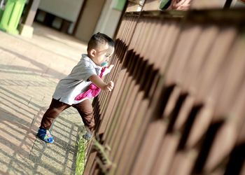 Boy standing on footpath by railing