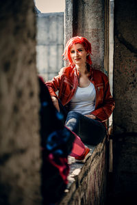 Portrait of young woman standing against building