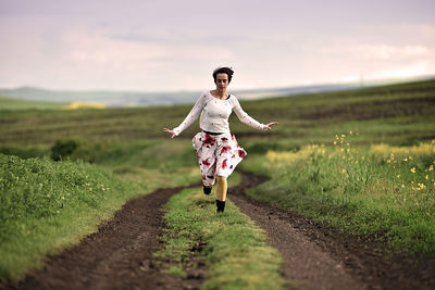 Full length of woman running on field against sky