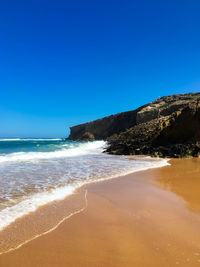 Scenic view of beach against clear blue sky