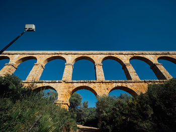 Low angle view of bridge against clear blue sky