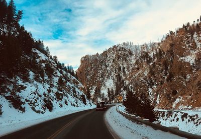 Road amidst mountains against sky during winter