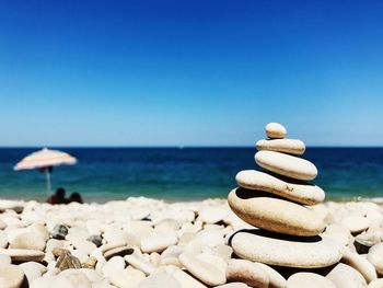 Stones on beach against clear blue sky