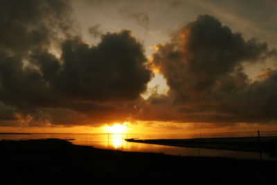 Scenic view of sea against dramatic sky during sunset