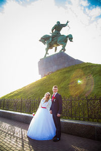 Rear view of bride and groom standing against statue