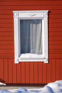 Carved white wooden platband on the background of the red wall, russia.