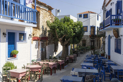 Chairs and tables at sidewalk cafe amidst buildings in city