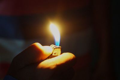Close-up of hand holding burning candle