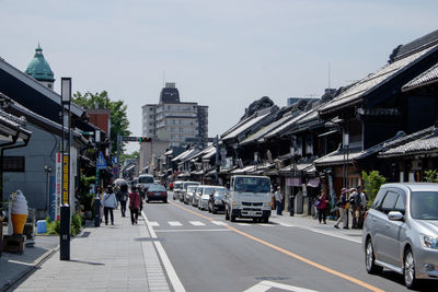 People walking on road in city against sky