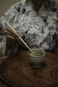 Close-up of hand holding bowl on table