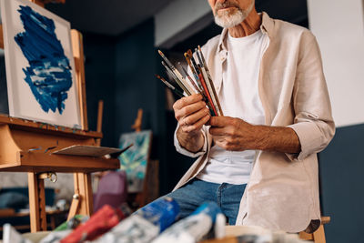 Midsection of man holding paper while standing at home