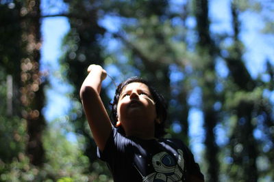 Boy looking up against trees