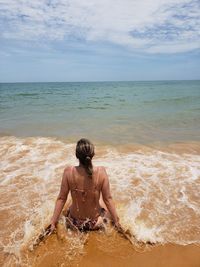 Rear view of shirtless man on beach against sky