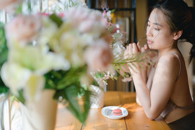 Side view of young woman sitting on table