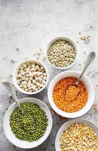 Bowls with different types of legumes on a gray concrete background