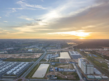 High angle view of city against cloudy sky at sunset