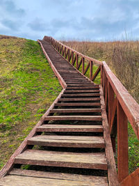 Wooden staircase on field against sky