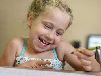 Smiling girl holding crayon at home