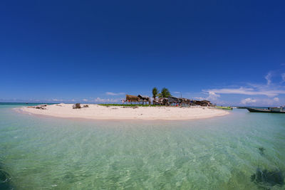 Scenic view of sea and island against blue sky