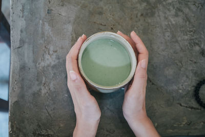 Directly above shot of hand holding tea cup