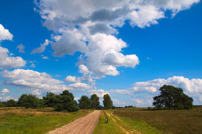 Road amidst field against sky