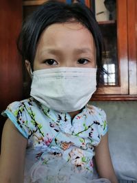 Close-up portrait of girl wearing mask at home