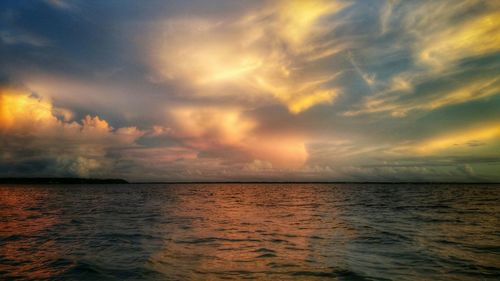 Scenic view of sea against cloudy sky at sunset