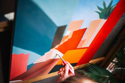 Cropped image of person holding paper against wall