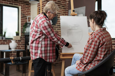 Senior teacher teaching student in drawing class