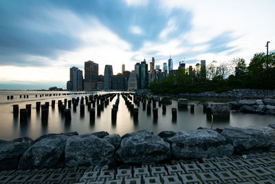 River by buildings against sky during sunset