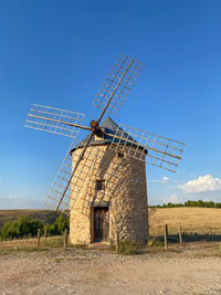 Traditional windmill on field against clear blue sky