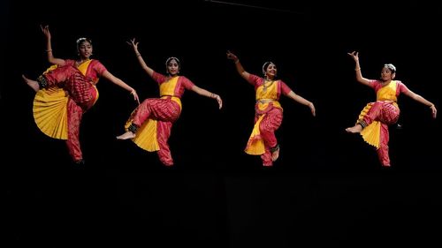 Group of people dancing against black background