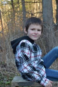 Cute boy sitting on land in forest