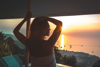 Midsection of woman against sea during sunset