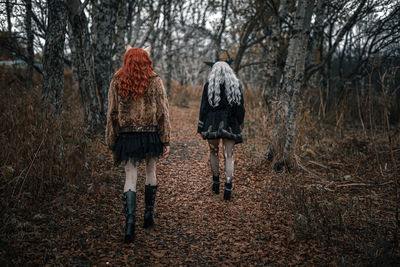 Rear view of two people walking in forest