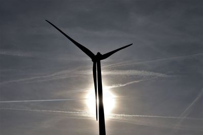 Low angle view of silhouette wind turbine against sky