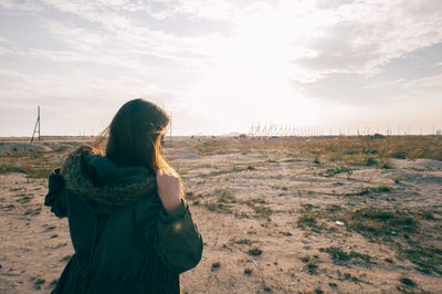 Rear view of woman standing at beach against sky