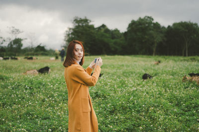 Side view portrait of young woman standing on grassy field