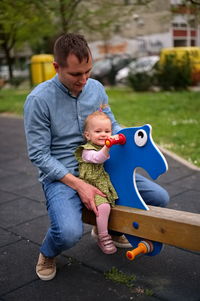 Father and his baby girl having fun on teeter at the playground
