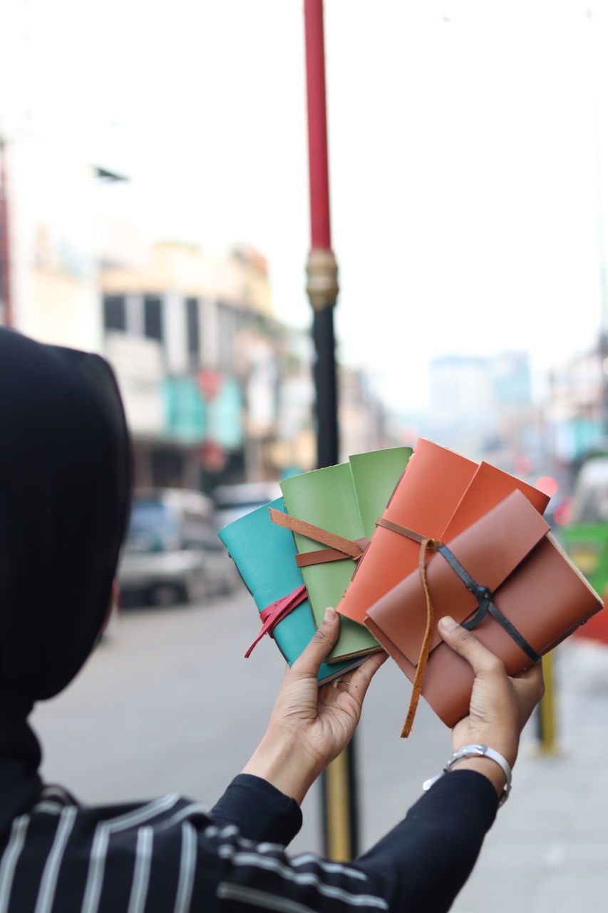 CLOSE-UP OF HAND HOLDING MULTI COLORED UMBRELLA