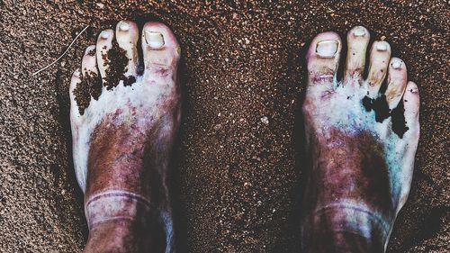 Low section of man wearing shoes on sand