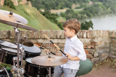 Little boy playing drums outdoors.