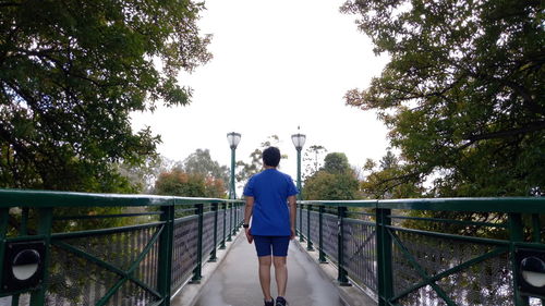 Rear view of woman standing on footbridge