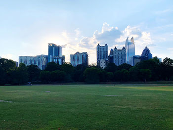 View of field and buildings against sky