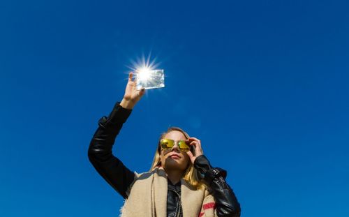 Low angle view of woman standing against clear blue sky