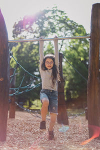 Portrait of a beautiful caucasian girl is doing push-ups on the horizontal bar in the the playgroun