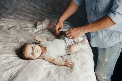 High angle view of father dressing baby in bedroom at home