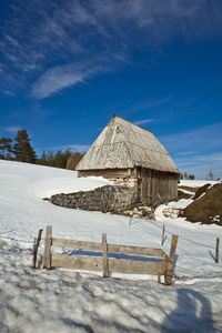 Built structure on snow covered field against sky