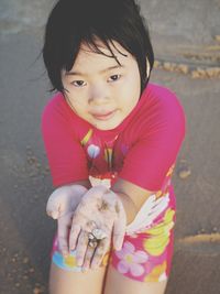 Close-up portrait of cute girl with pink sitting outdoors