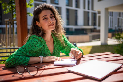 Young woman using mobile phone while sitting on table